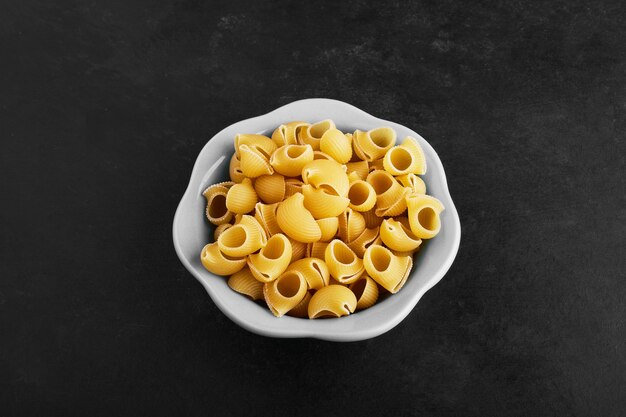 Variedades de pasta cruda en taza de cerámica en negro.