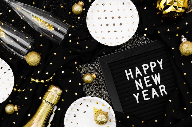 Foto gratuita varios accesorios y gafas sobre fondo negro y tarjeta de feliz año nuevo