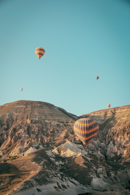 Varios coloridos globos aerostáticos flotando sobre las montañas