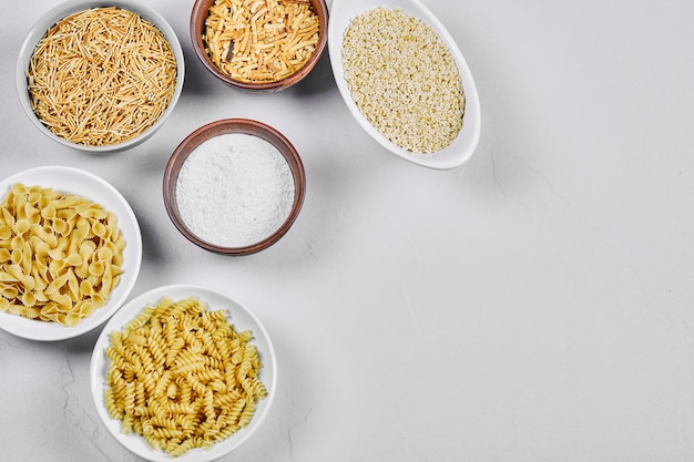 Varios cuencos de pasta cruda en blanco con harina.