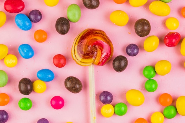 Foto gratuita varios dulces dulces rodeando piruleta sobre fondo rosa