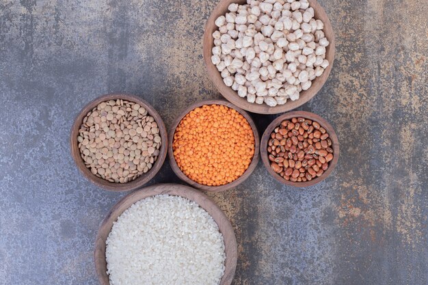 Varios frijoles, lentejas y arroz en tazones de madera.