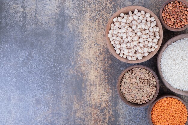 Varios frijoles, lentejas y arroz en tazones de madera.