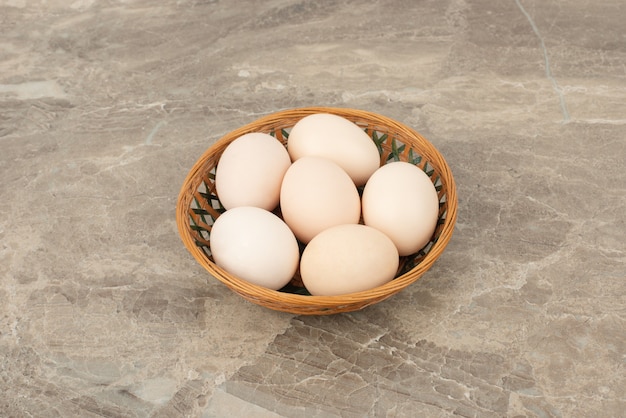 Varios huevos blancos en una canasta de mimbre