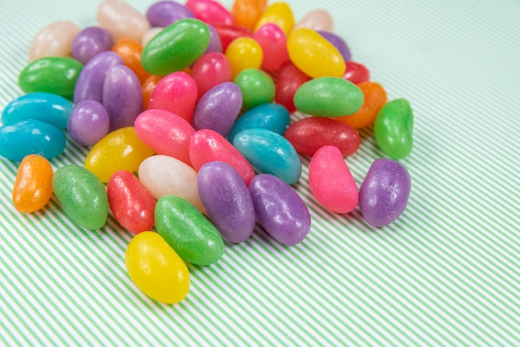 Foto gratuito varios jelly beans sobre fondo de rayas verdes con blanco