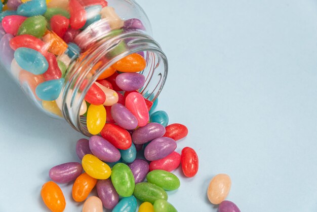 Varios Jelly Beans en la superficie azul dentro de la olla de vidrio