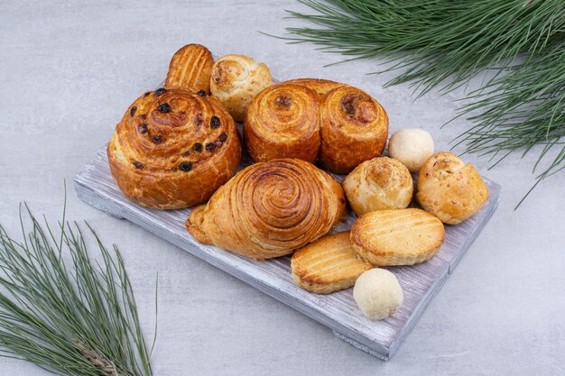 Varios pasteles dulces y rollos con galletas sobre tabla de madera. Foto de alta calidad