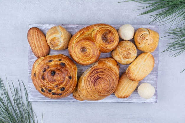 Varios pasteles dulces y rollos con galletas sobre tabla de madera.