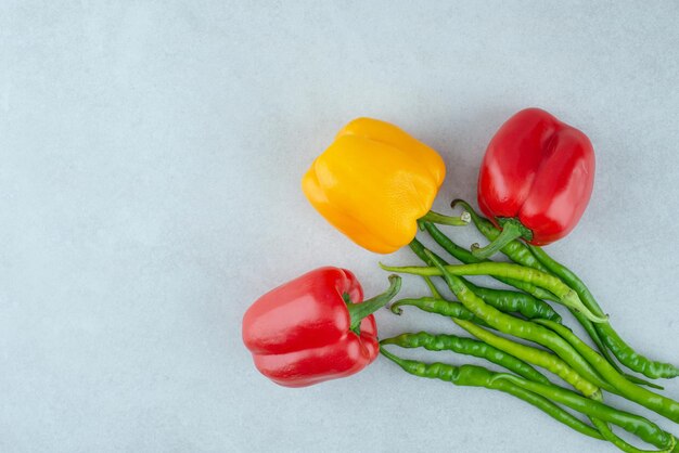 Varios pimientos y chiles sobre superficie azul.