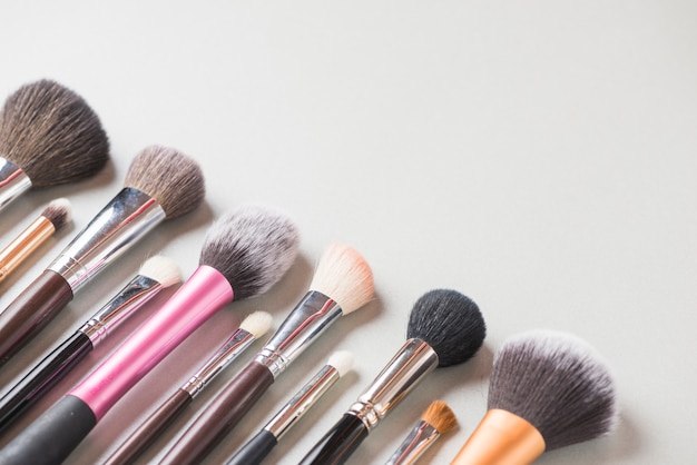 Varios pinceles de maquillaje dispuestos en una fila sobre fondo blanco