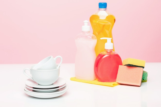 Varios platos, esponjas de cocina y botellas de plástico con jabón líquido natural para lavar platos para lavar los platos a mano.