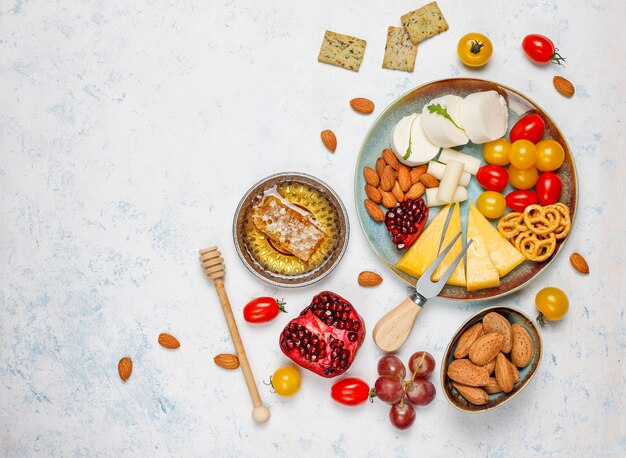 Varios platos de queso y queso en la mesa de luz con diferentes nueces y frutas