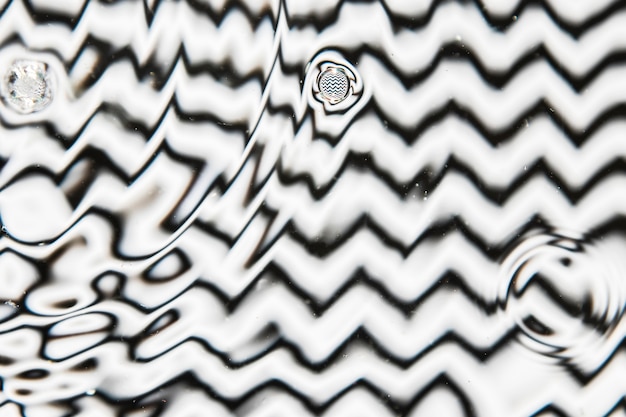 Varios tamaños de gota de agua sobre una superficie de piscina en blanco y negro