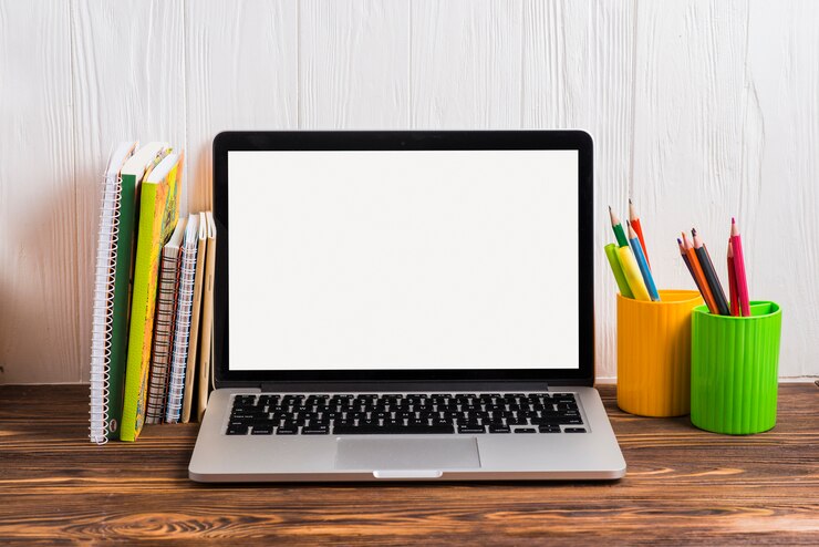 Foto gratuito varios tipos de libros cerca de la computadora portátil con pantalla blanca en blanco en el escritorio de madera