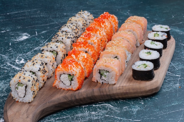 Varios tipos de rollos de sushi servidos en bandeja de madera.