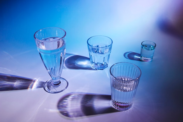 Varios tipos de vasos con bebidas en el fondo azul