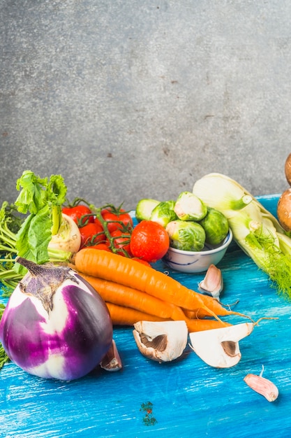 Varios vegetales orgánicos frescos en superficie de madera azul