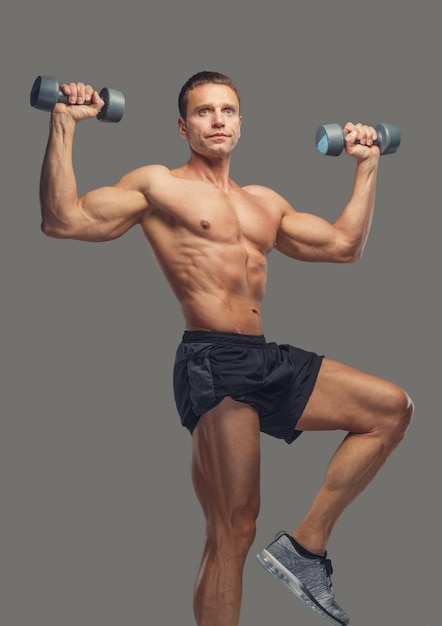 Foto gratuita varón deportivo de mediana edad con pesas aislado sobre fondo gris.