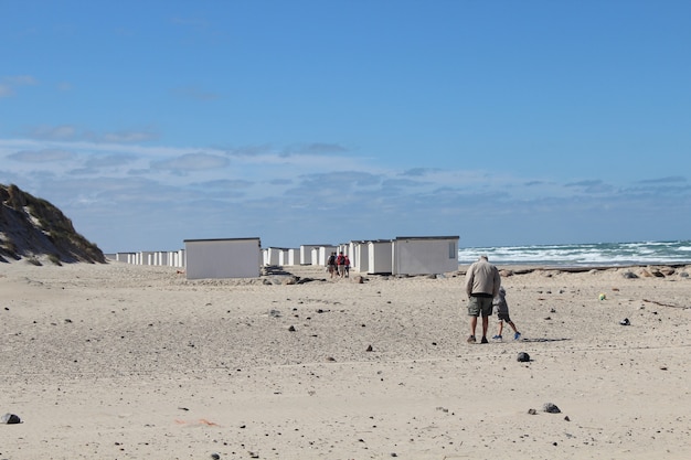 Varón de edad y su nieto caminando en el campamento junto al mar en Lokken, Dinamarca