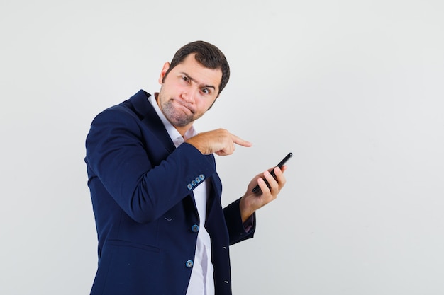 Varón joven apuntando al teléfono móvil en camisa