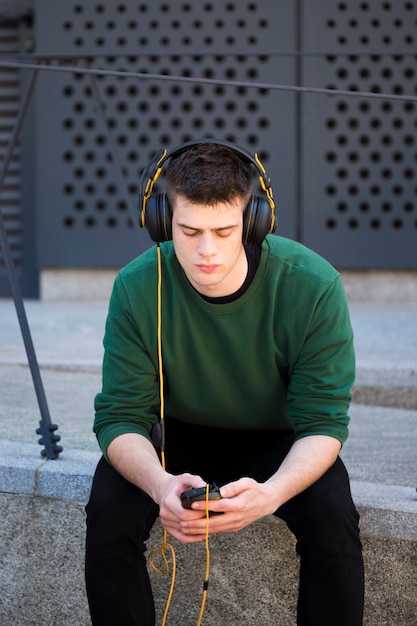 Varón joven con auriculares escuchando música.