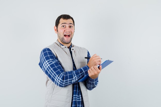 Varón joven en camisa, chaqueta notando algo y mirando contento