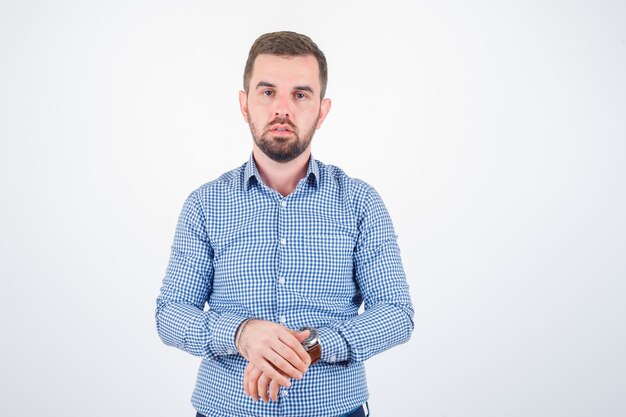 Varón joven en camisa posando mientras mira a la cámara y parece seguro de sí mismo, vista frontal.