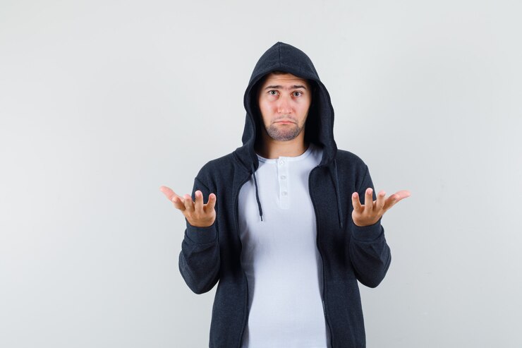 Foto gratuito varón joven en camiseta, chaqueta mostrando gesto de impotencia y mirando confundido, vista frontal.