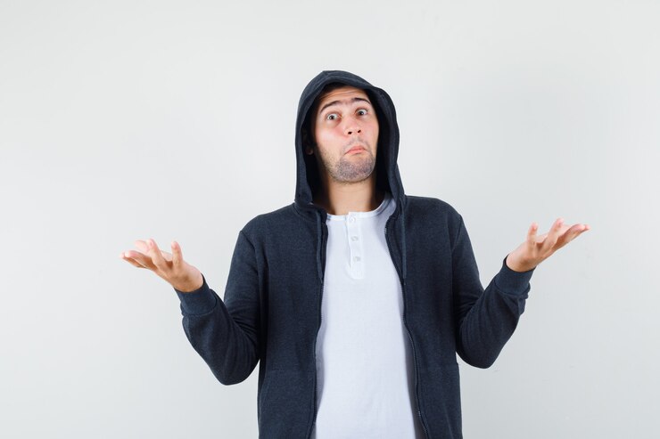 Foto gratuito varón joven en camiseta, chaqueta mostrando gesto de impotencia y mirando confundido, vista frontal.