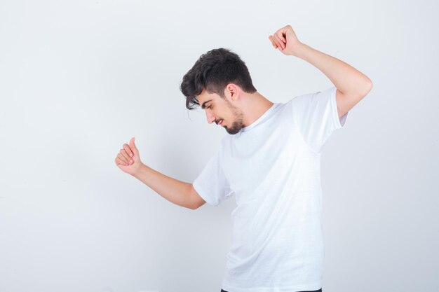 Varón joven en camiseta posando mientras está de pie y mirando confiado, vista frontal.