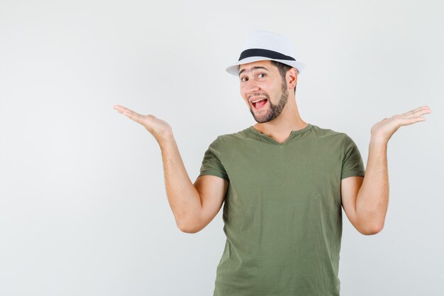 Varón joven en camiseta verde y sombrero haciendo gesto de escalas y mirando alegre