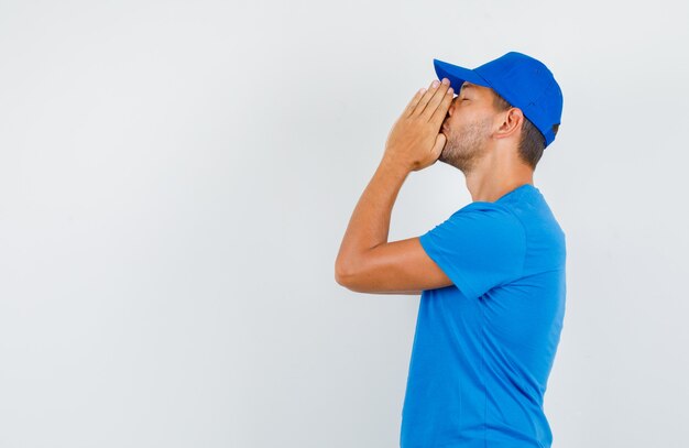 Varón joven cogidos de la mano en gesto de oración en camiseta azul