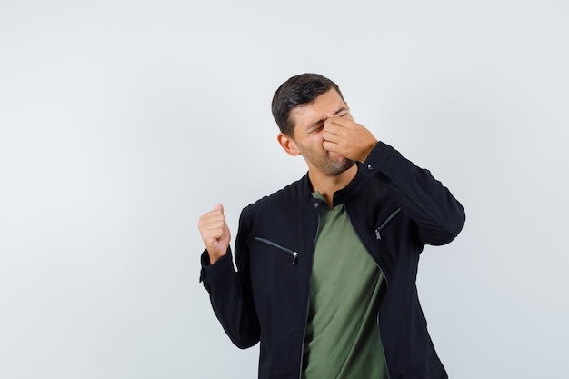 Foto gratuita varón joven frotándose los ojos y la nariz en camiseta, chaqueta y mirando fatigado, vista frontal.