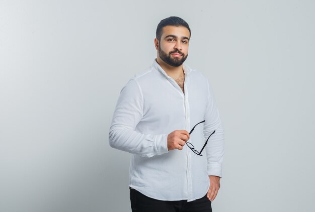 Varón joven con gafas en camisa blanca, pantalones y guapo