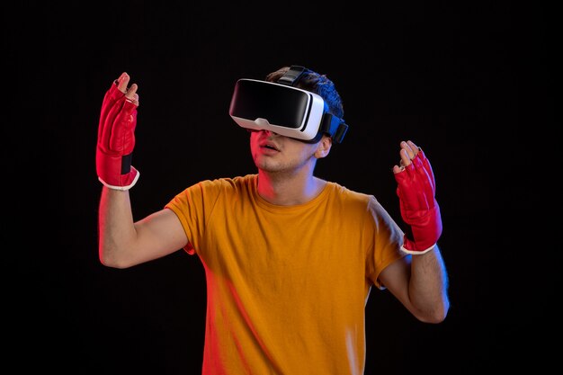 Varón joven jugando realidad virtual en guantes de mma en escritorio oscuro gaming d tech visual