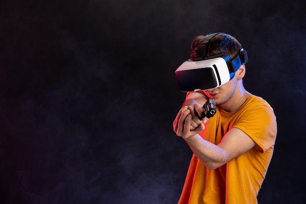Varón joven jugando realidad virtual con pistola en un video de tecnología de juegos oscuros