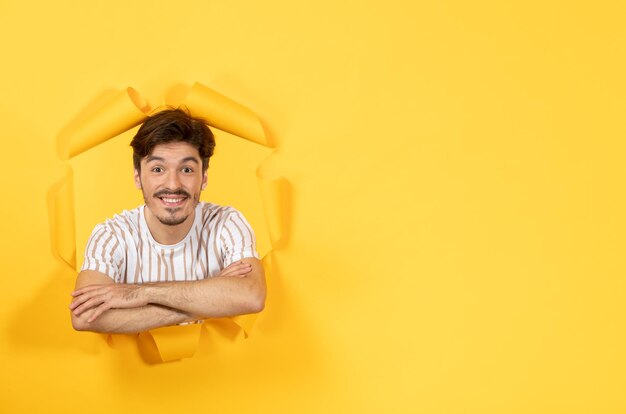 Varón joven mirando y de pie sobre fondo de papel amarillo rasgado chico venta interior facial