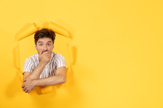 Foto gratuita varón joven mirando y de pie sobre fondo de papel amarillo rasgado facial chico interior venta