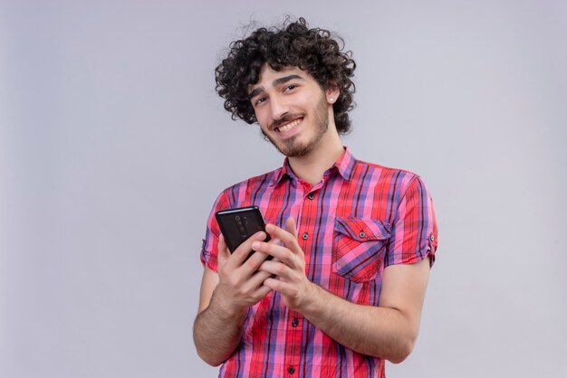 Varón joven pelo rizado aislado camisa colorida smartphone sonriendo