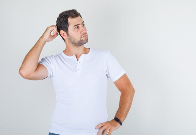 Varón joven posando con las manos en la cintura y el cuello en camiseta blanca