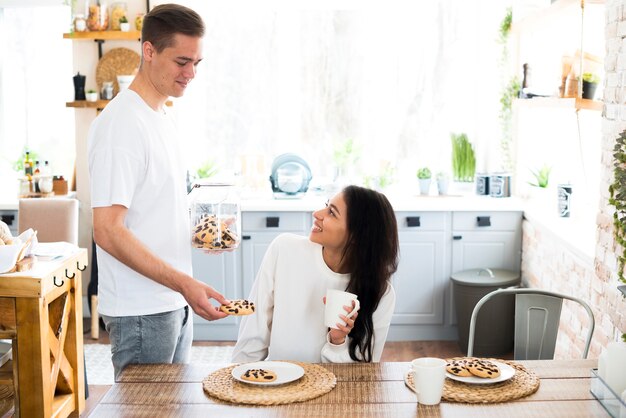 Varón joven que da las galletas a la novia étnica