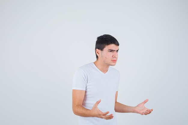 Varón joven que finge atrapar algo en camiseta y parece serio. vista frontal.