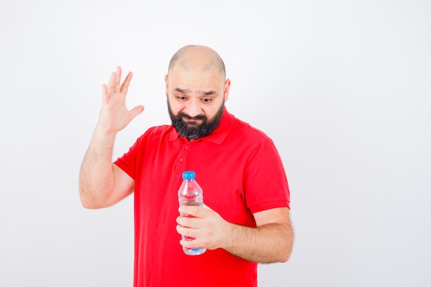 Foto gratuita varón joven que mira la botella en la vista frontal de la camisa roja.