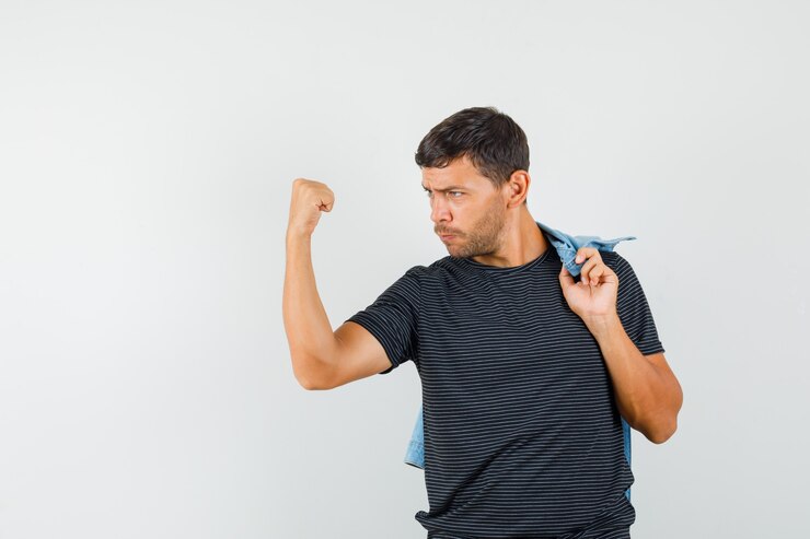 Foto gratuito varón joven que muestra el gesto del ganador mientras sostiene la chaqueta en la camiseta