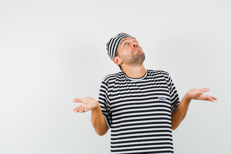 Foto gratuito varón joven que muestra un gesto de impotencia en el sombrero de camiseta a rayas y mirando desconcertado