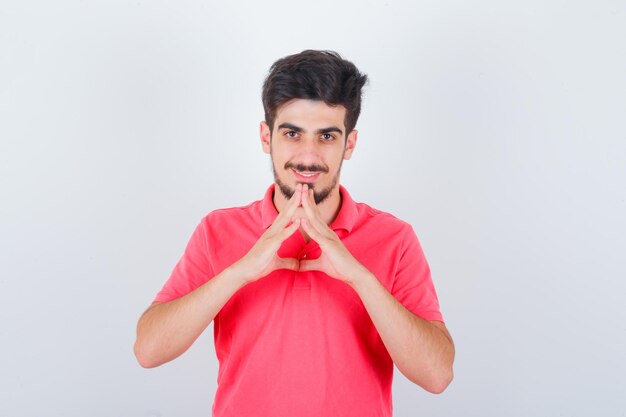 Varón joven que muestra el gesto del triángulo en la camiseta y que mira linda, vista frontal.