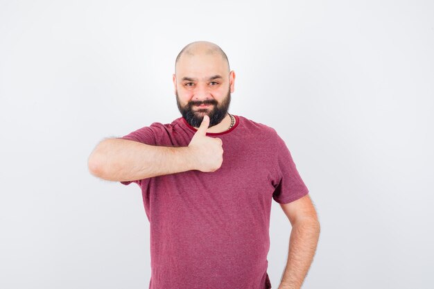 Varón joven que muestra el pulgar hacia arriba en la camiseta y parece confiado. vista frontal.