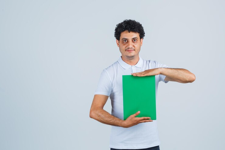 Foto gratuito varón joven que sostiene el portapapeles en camiseta blanca, pantalones y un aspecto elegante. vista frontal.