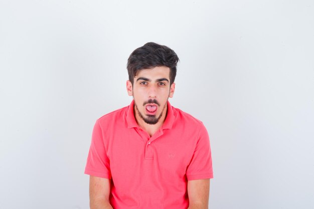 Varón joven sacando la lengua en camiseta rosa y mirando divertido, vista frontal.