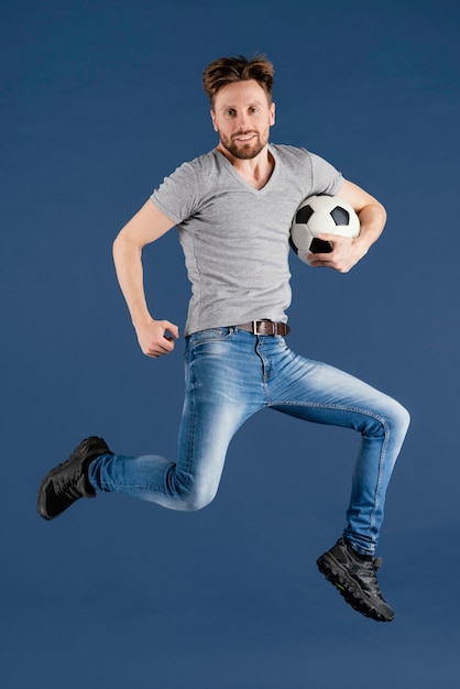 Foto gratuita varón joven saltando con pelota de fútbol